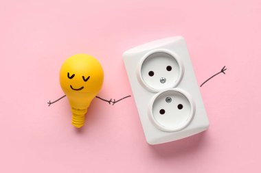Yüzü çizilmiş komik bir ampul ve pembe arka planda elektrik prizi. Dostluk Günü kutlaması