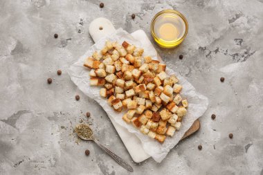 Kıtır kıtır ekmek, biber ve gri arka planda cam bir kase yağ.