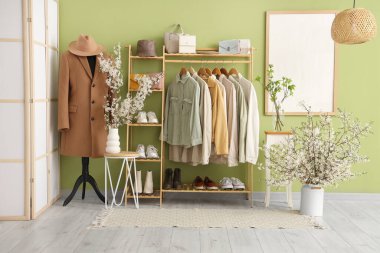 İçinde elbise askılığı, katlanan ekran, manken ve masalardaki vazolarda açan güzel dallar olan oturma odasının içi.