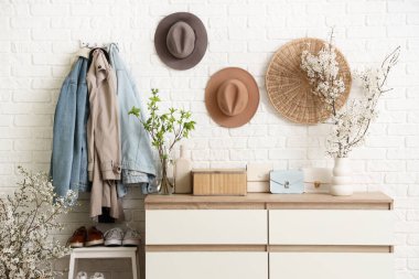 Sallanan giysiler, merdiven ve komodindeki vazolarda açan güzel dallarla oturma odasının içinde.