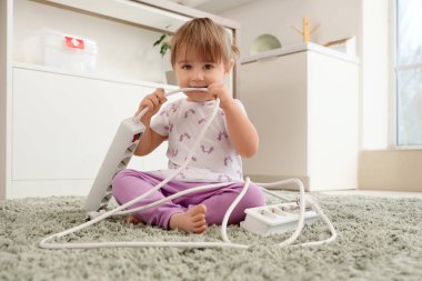 Mutfakta küçük tatlı bir kız çiğneme kablosu. Tehlikedeki çocuk