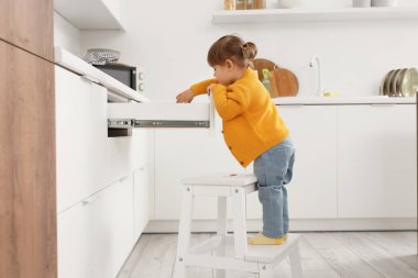 Mutfakta açık çekmecesi olan sevimli küçük bir kız. Tehlikedeki çocuk