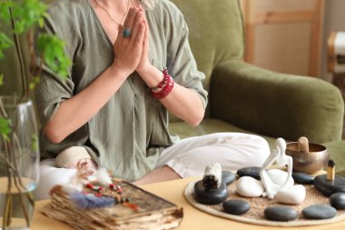 Kadın kanepede otururken meditasyon yapıyor.