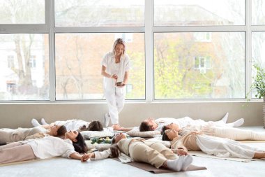 Bir grup insan yerde yatarken meditasyon yapıyor.