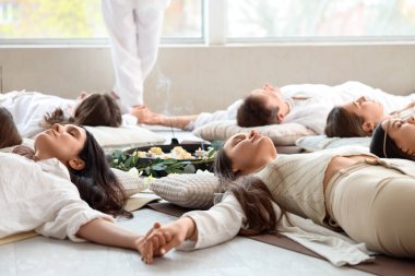 Bir grup insan yerde yatarken meditasyon yapıyor.