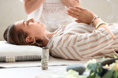 Şifacı meditasyon yapan genç bir kadınla çalışıyor.