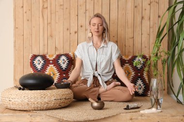 Evde yoga yaparken meditasyon yapan bir kadın.