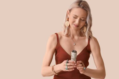 Alan için yanan beyaz adaçayı olan kadın bej arka planda temizlik yapıyor.