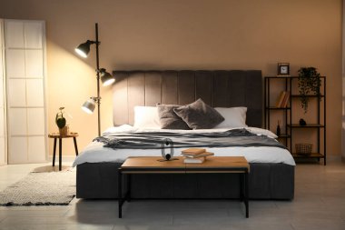 Rahat gri yataklı ve geceleri parlayan lambasıyla yatak odasının şık bir iç mekanı.