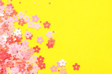 Sarı arka planda çiçek şeklinde güzel pembe konfeti.