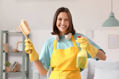 Yatak odasında temizlik fırçası ve deterjanı olan kadın hademe.