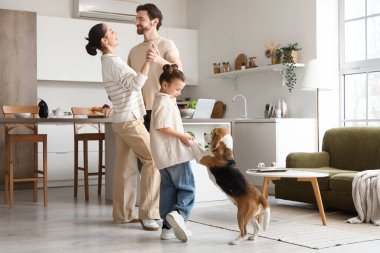 Anne babasıyla küçük şirin bir kız ve mutfakta dans eden Beagle köpeği.