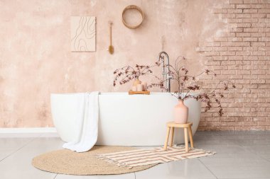 Çiçek açan dalları ve odada pembe grunge duvarının yanında küveti olan vazolar.