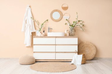 Lavabosu, dalları ve pufları olan banyonun içi.