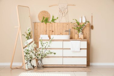 Lavabo, çiçek açan dallar ve aynalarla dolu bir banyo.