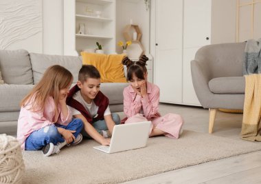 Evde dizüstü bilgisayar kullanan küçük arkadaşlar.