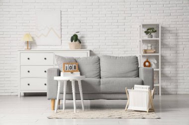 Oturma odasının içinde kanepe, dergi standı ve masada takvim var.