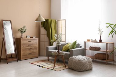 Katlanmış perdeli kanepe, oturma odasındaki pencerenin yanında beyaz çiçek açan vazolar.