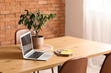 Dizüstü bilgisayarlı ve yemek masasına yerleştirilmiş.