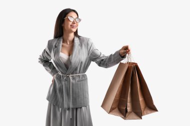 Beyaz arka planda alışveriş torbaları olan, güneş gözlüklü zarif genç bir kadın.