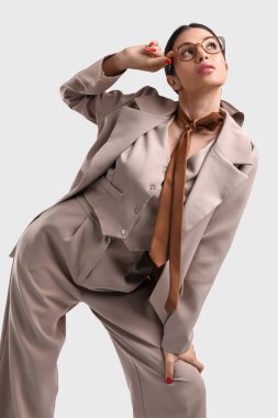 Beyaz arka planda bej takım elbiseli zarif genç bayan.