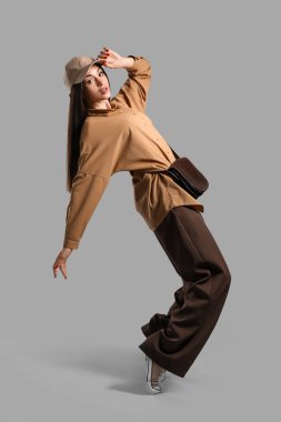 Gri arka planda şapkalı şık genç kadın