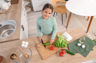 Mutfak masasında salatalık kesen tatlı bir kız.