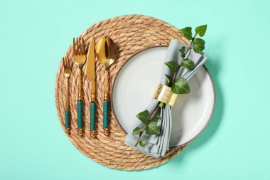 Altın çatal bıçak takımı ve turkuaz arka planda ağaç dalı olan güzel bir masa.