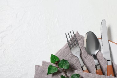 Gümüş çatal bıçak takımları ve beyaz arka planda ağaç dalları olan güzel bir masa.