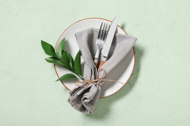 Gümüş çatal bıçak takımı ve yeşil arka planda taze yapraklarla güzel bir masa.
