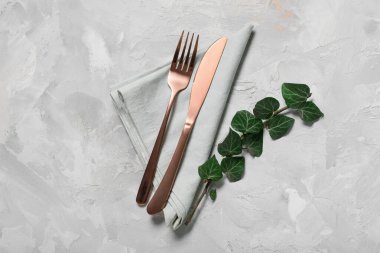 Gri arkaplanda paslanmaz çatal bıçak ve ağaç dalları