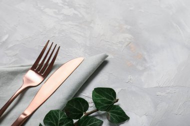 Gri arkaplanda paslanmaz çatal bıçak ve ağaç dalları, yakın plan