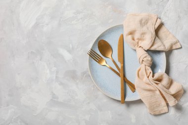 Gri arkaplanda altın çatal bıçak seti olan güzel bir masa.