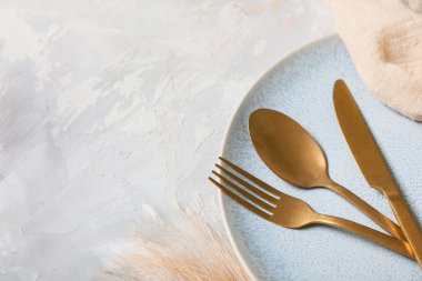 Gri arka planda altın çatal bıçak seti olan güzel bir masa, yakın plan.