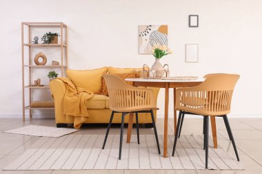 Yemek masası, sarı kanepe ve raf ünitesi olan ışık odasının içinde.