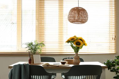 Ayçiçekli vazo, kitaplar ve yemek masasında bitki.