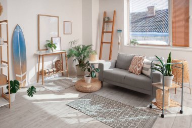 Gri kanepesi, çiçekleri ve sörf tahtası olan şık bir oturma odası.