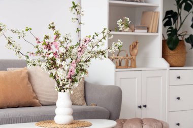 Oturma odasındaki masanın üzerinde çiçek açan bir vazo.