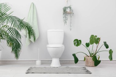 Seramik klozet, fırça ve çiçekli şık bir tuvalet.