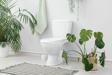 Seramik klozet, fırça ve çiçekli şık bir tuvalet.