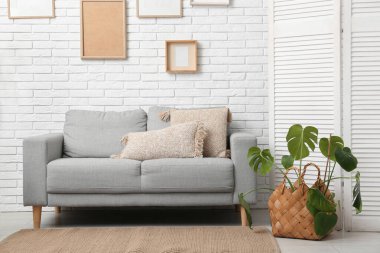 Gri kanepesi, çerçeveleri, çiçekleri ve katlanır perdesi olan şık bir oturma odası.