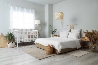 İçinde yatak, bebek yatağı ve masalar olan bir oda.