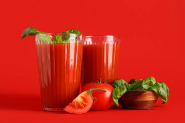 Kırmızı arka planda fesleğenli taze domates suyu.