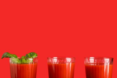 Kırmızı arka planda fesleğenli taze domates suyu.