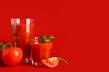 Kırmızı arka planda fesleğenli taze domates suyu.