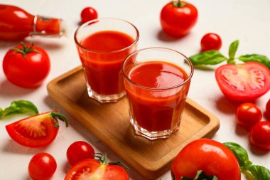 Beyaz arka planda fesleğen ve sebzeli taze domates suyu, yakın plan.