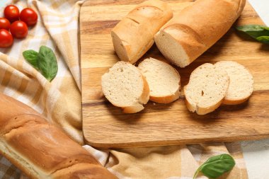 Açık mavi arkaplanda taze baget, fesleğen ve kiraz domatesli ahşap tahta, yakın plan.