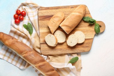 Açık mavi arka planda taze baget, fesleğen ve kiraz domatesli ahşap tahta.