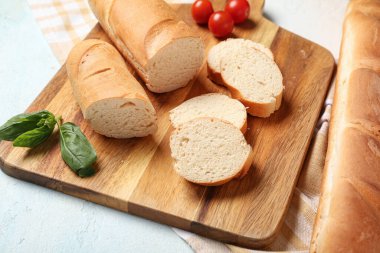 Açık mavi arkaplanda taze baget, fesleğen ve kiraz domatesli ahşap tahta, yakın plan.