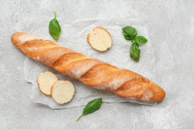 Taze baget ekmeği ve gri arka planda fesleğen.